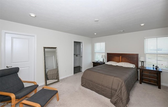 bedroom featuring multiple windows, ensuite bath, and light colored carpet