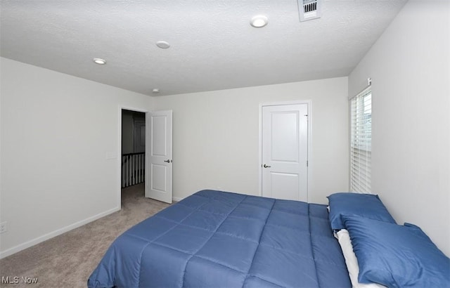 bedroom with light colored carpet and a textured ceiling