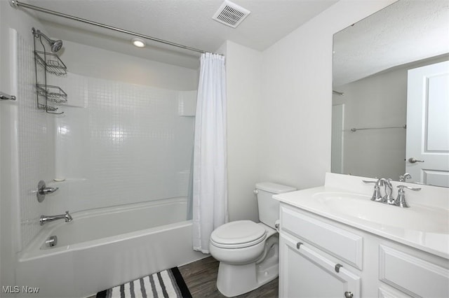 full bathroom featuring hardwood / wood-style floors, vanity, toilet, a textured ceiling, and shower / bath combo with shower curtain