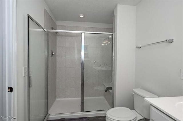 bathroom featuring vanity, toilet, and a shower with shower door