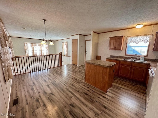 kitchen featuring sink, dark wood-type flooring, an inviting chandelier, a textured ceiling, and a kitchen island