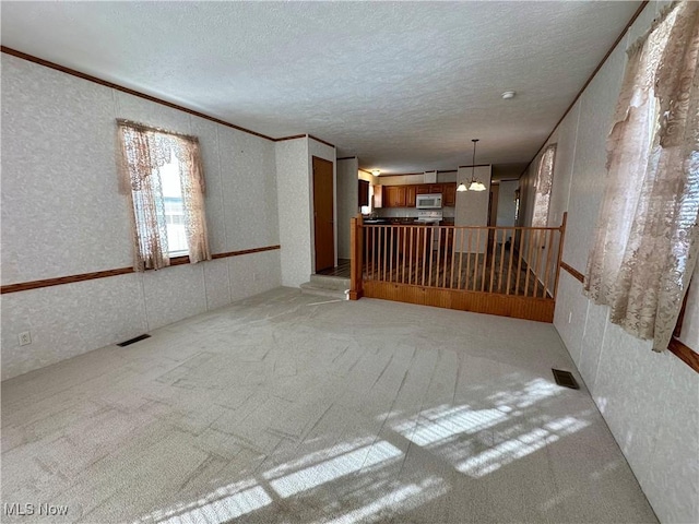 carpeted spare room featuring a chandelier and a textured ceiling