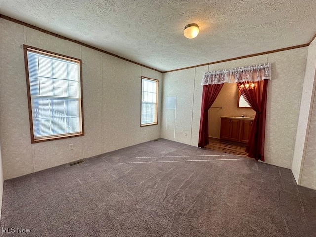 spare room with plenty of natural light, dark carpet, and a textured ceiling