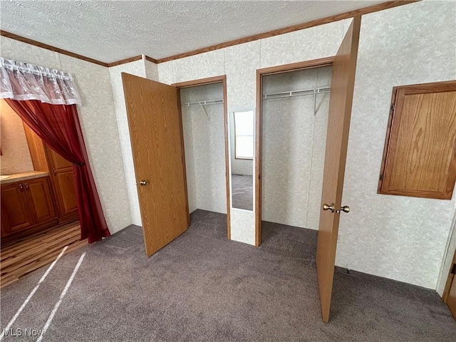 unfurnished bedroom featuring crown molding, dark carpet, and a textured ceiling