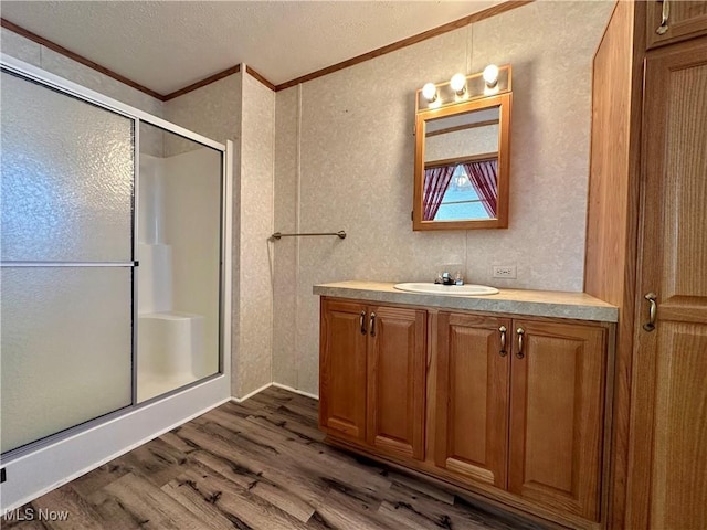 bathroom with hardwood / wood-style floors, vanity, ornamental molding, and walk in shower