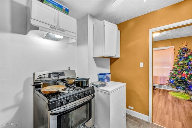 kitchen featuring black gas range, white cabinetry, white fridge, a textured ceiling, and hardwood / wood-style flooring