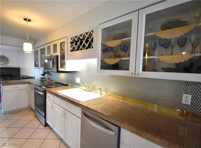 kitchen featuring white cabinetry, sink, stainless steel appliances, decorative light fixtures, and decorative backsplash