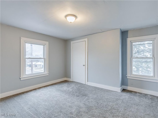 carpeted spare room featuring baseboards and plenty of natural light