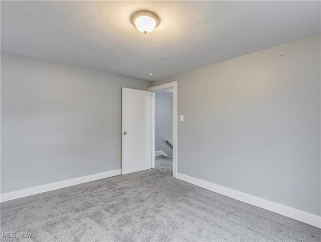 carpeted empty room featuring baseboards