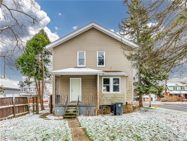 snow covered back of property featuring a porch