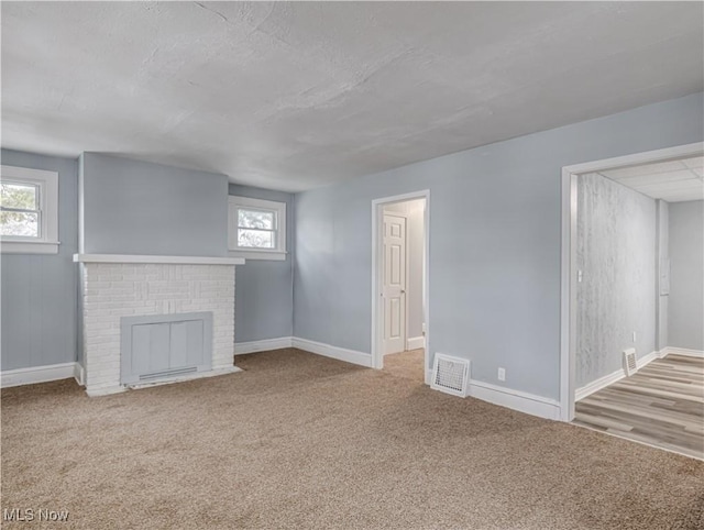 unfurnished living room featuring light carpet and a brick fireplace