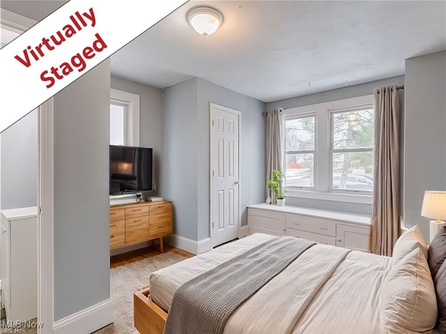 bedroom with baseboards, wood finished floors, and multiple windows
