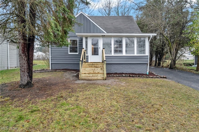 view of front of house featuring a sunroom and a front lawn