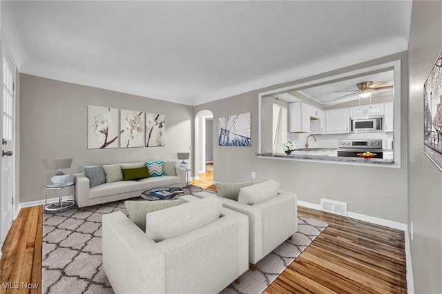 living room with hardwood / wood-style flooring, ceiling fan, and sink