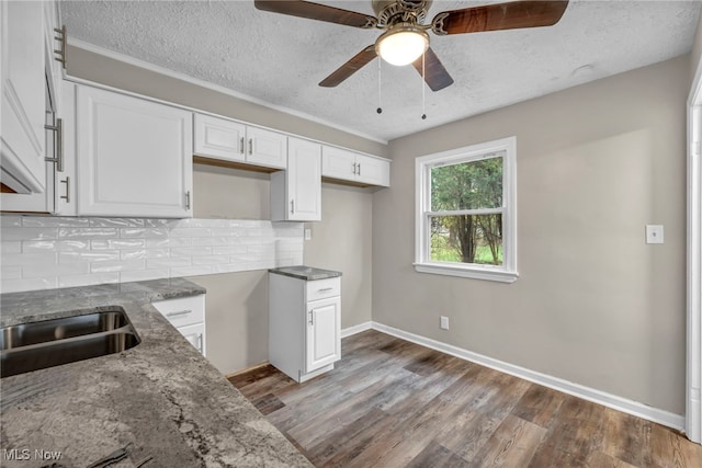 kitchen with white cabinets, backsplash, hardwood / wood-style floors, and a textured ceiling