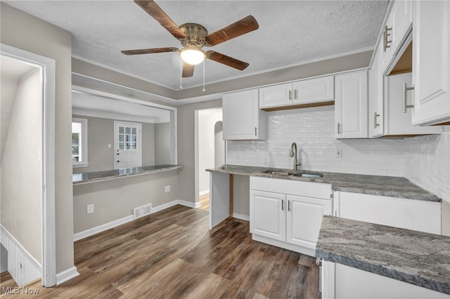 kitchen with white cabinetry, sink, dark hardwood / wood-style floors, backsplash, and a textured ceiling