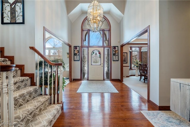 entryway with light hardwood / wood-style flooring, a towering ceiling, and an inviting chandelier