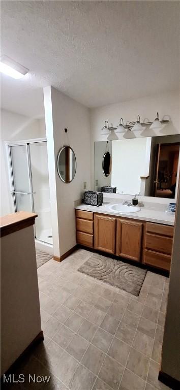 bathroom with vanity, a textured ceiling, and a shower with shower door