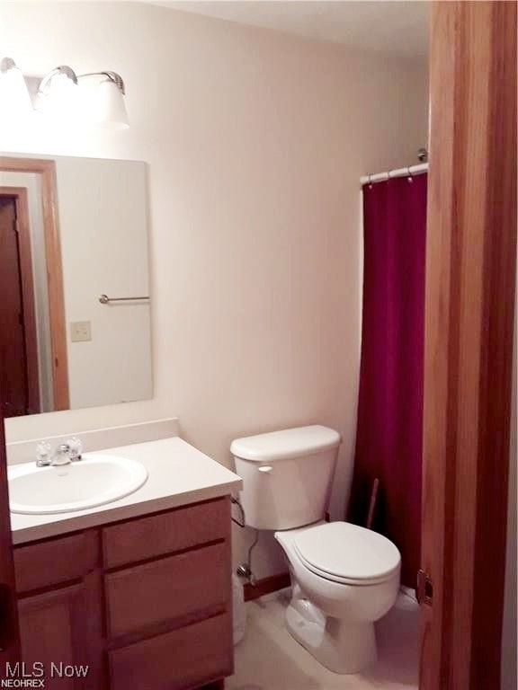 bathroom with walk in shower, vanity, and toilet