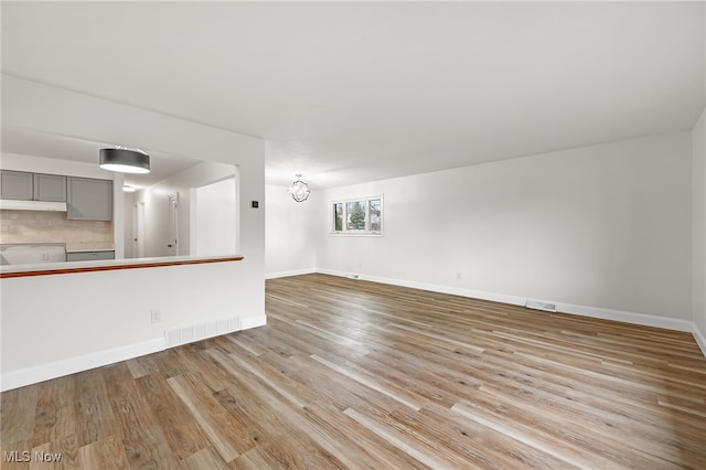 unfurnished living room with light hardwood / wood-style flooring and an inviting chandelier