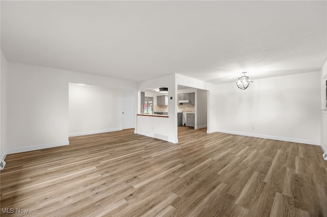 unfurnished living room with hardwood / wood-style floors and an inviting chandelier