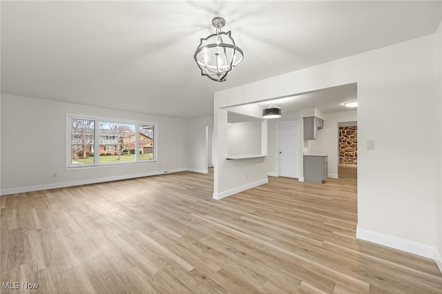 unfurnished living room featuring light wood-type flooring and a notable chandelier