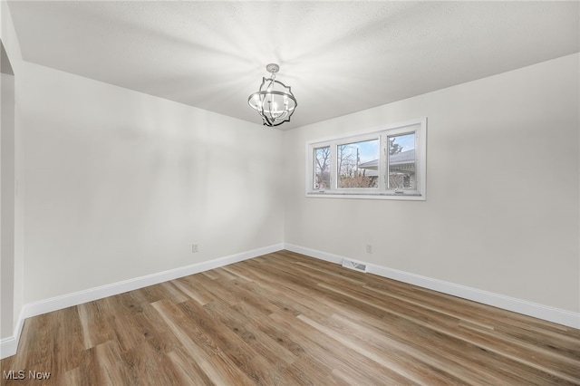 unfurnished room featuring a notable chandelier and wood-type flooring