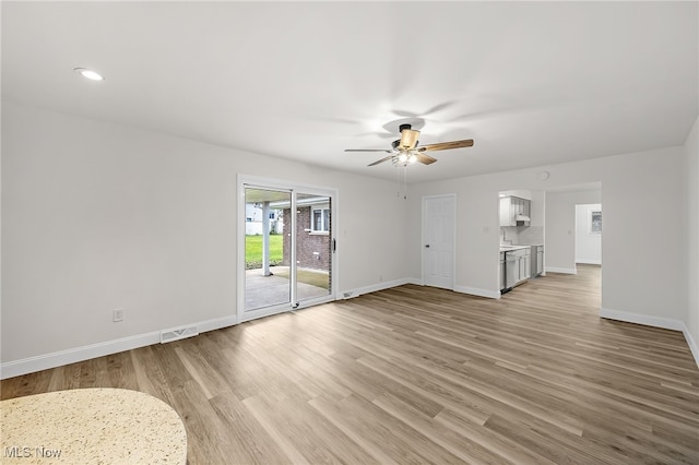 unfurnished living room featuring light hardwood / wood-style floors, ceiling fan, and sink