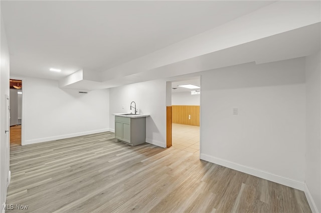 basement featuring sink and light wood-type flooring