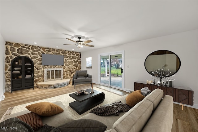 living room with ceiling fan, a fireplace, and light hardwood / wood-style flooring