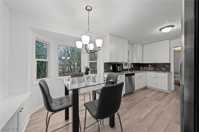 kitchen with tasteful backsplash, stainless steel appliances, light hardwood / wood-style flooring, white cabinets, and hanging light fixtures