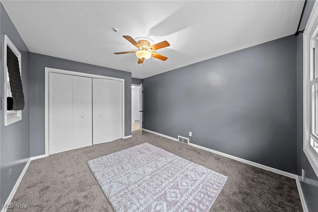 unfurnished bedroom featuring ceiling fan, a closet, carpet, and baseboards