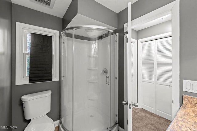 bathroom with a shower with door, vanity, and toilet