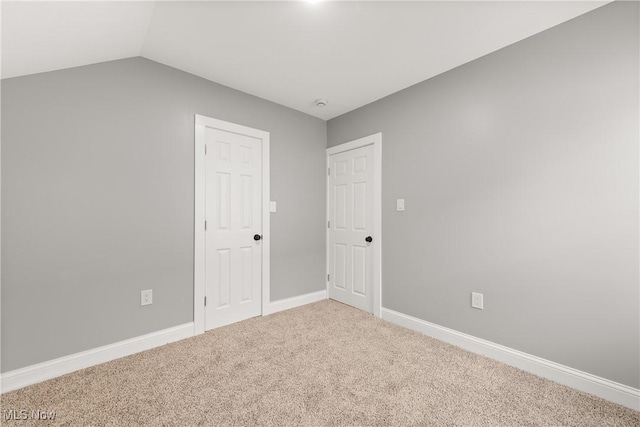 carpeted spare room featuring vaulted ceiling