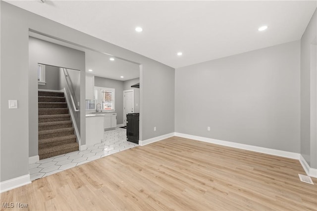 unfurnished living room featuring light hardwood / wood-style floors and sink