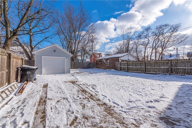 snowy yard featuring an outdoor structure and a garage