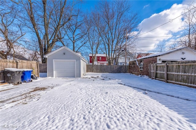 yard layered in snow featuring an outbuilding and a garage