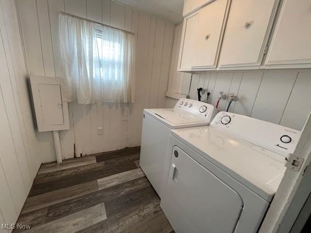 laundry area featuring electric panel, cabinets, washer and clothes dryer, and dark wood-type flooring