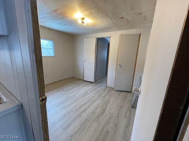 unfurnished room featuring light hardwood / wood-style floors and wood walls