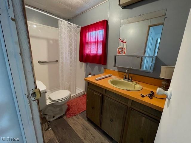 bathroom with a shower with shower curtain, vanity, hardwood / wood-style flooring, and toilet