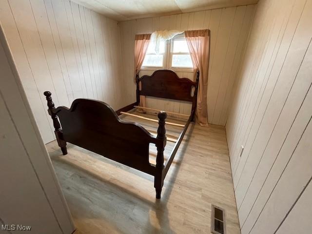 bedroom featuring wooden walls and light hardwood / wood-style floors