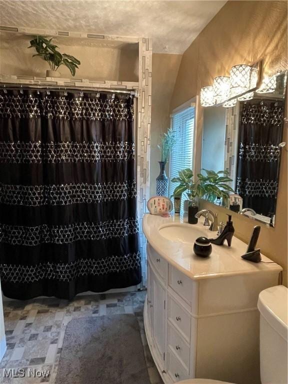 bathroom with a textured ceiling, vanity, toilet, curtained shower, and lofted ceiling