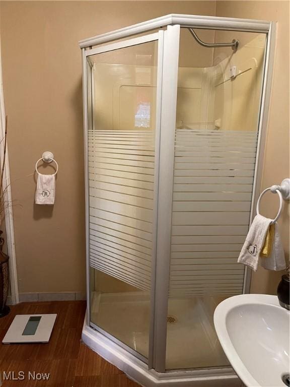 bathroom featuring hardwood / wood-style flooring, a shower with shower door, and sink