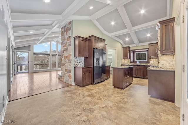 kitchen with vaulted ceiling with beams, stainless steel fridge, light wood-type flooring, tasteful backsplash, and a kitchen island