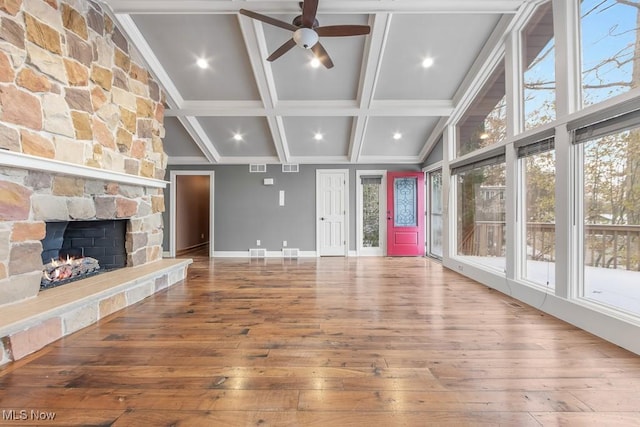 unfurnished living room with wood-type flooring, vaulted ceiling with beams, a stone fireplace, and ceiling fan