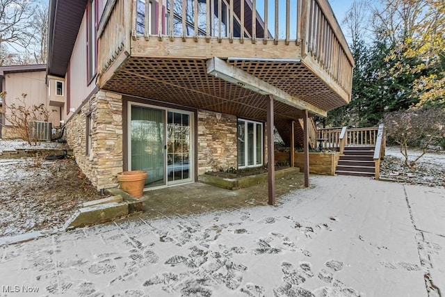 snow covered back of property featuring central air condition unit