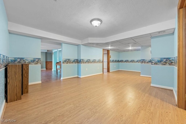 spare room with a drop ceiling, wood-type flooring, and a textured ceiling