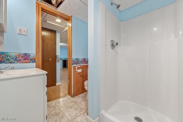 bathroom with toilet, tile patterned flooring, vanity, and walk in shower