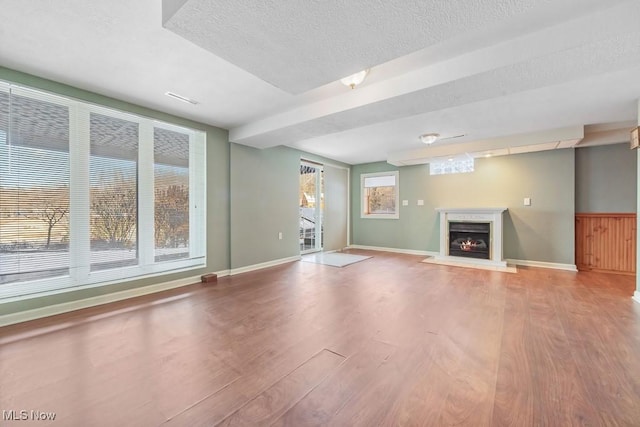 unfurnished living room featuring hardwood / wood-style flooring and a textured ceiling