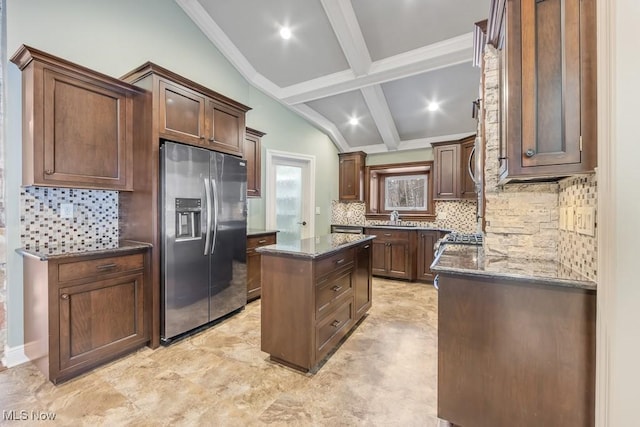 kitchen with sink, a center island, backsplash, dark stone countertops, and appliances with stainless steel finishes